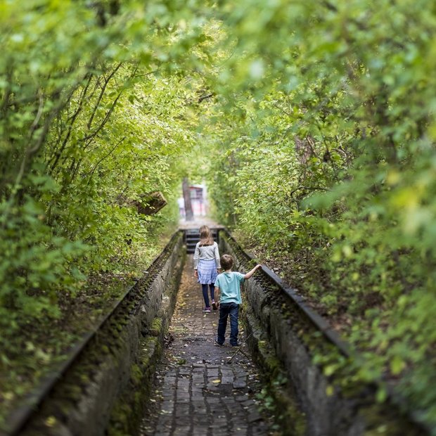 Zwei Kinder laufen dem Verlauf alter Gleise im Natur Park Südgelände nach