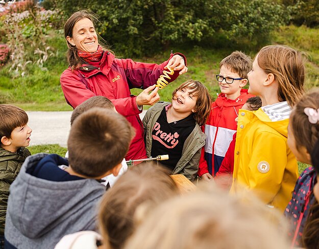 Eine Frau zeigt Kindern eine Apfelschalenspirale