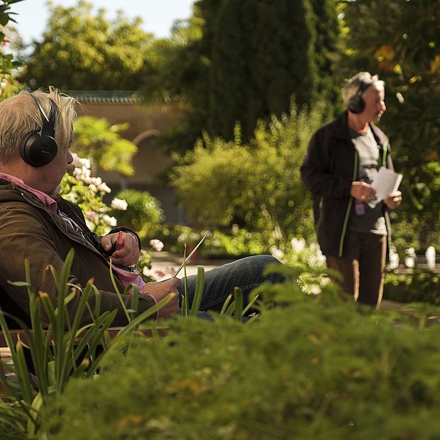 Zwei Personen mit Kopfhörern nehmen an einem Audio-Walk durch die Gärten der Welt teil