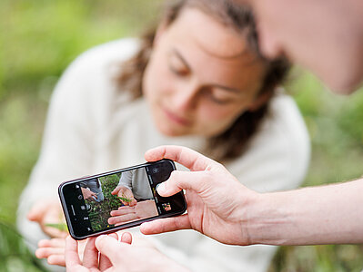 Eine Person fotografiert eine Pflanze mit ihrem Handy
